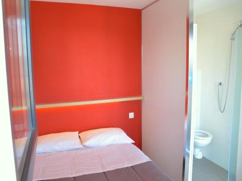 a red room with a bed and a toilet at Eklo Hotels Le Havre in Le Havre