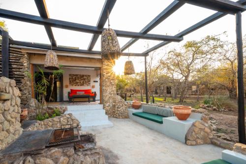 an outdoor patio with a stone wall and a pergola at Foxy Crocodile Bush Lodge & Kruger Safari's - No Loadshedding in Marloth Park
