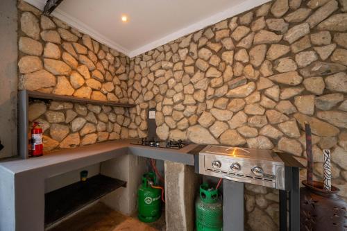 a kitchen with a stone wall with a stove at Foxy Crocodile Bush Lodge & Kruger Safari's - No Loadshedding in Marloth Park
