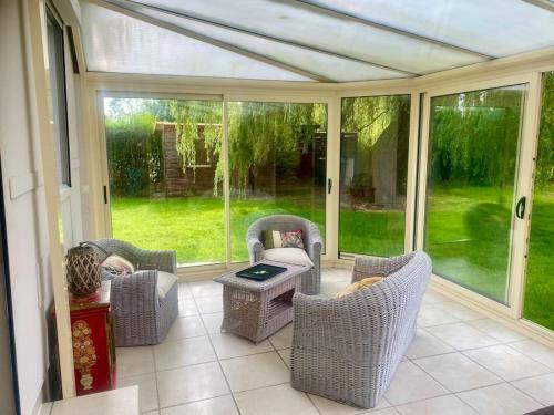 a screened in porch with wicker chairs and a table at Le gîte du marais in Suzanne