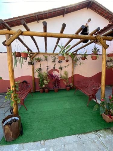 a pergola with potted plants and a green floor at Suite3 a 3 quadras da praia in Bertioga