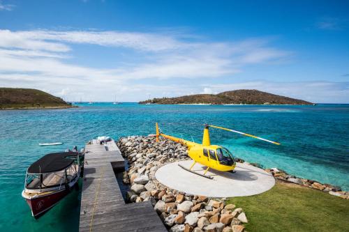 a yellow helicopter parked on a dock next to a boat at Saba Rock Resort in Virgin Gorda
