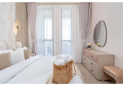 a white bedroom with a large bed and a mirror at Bright and Modern 1BR Midtown Near Expo Site by Vibel in Dubai