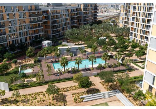 an aerial view of a pool with palm trees and buildings at Bright and Modern 1BR Midtown Near Expo Site by Vibel in Dubai