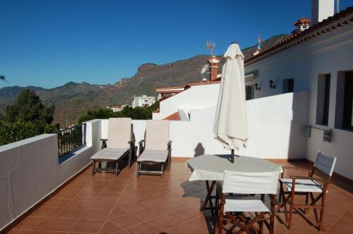 a patio with a table and chairs and an umbrella at VV El Almendro in Tejeda