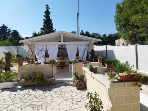 a gazebo in a yard with potted plants at Villa Grace in Selva di Fasano