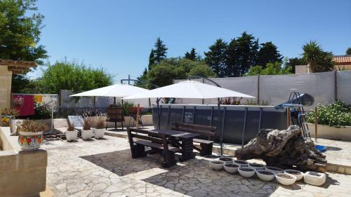 a patio with a bench and umbrellas and plants at Villa Grace in Selva di Fasano