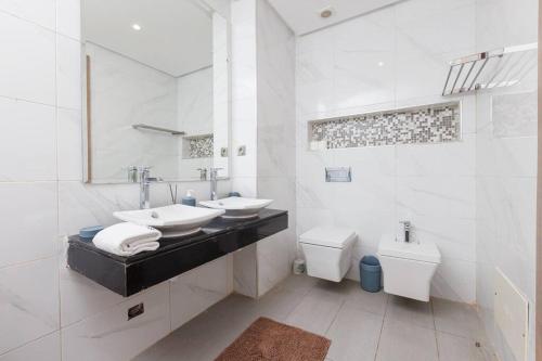 a white bathroom with two sinks and a toilet at Elegant 2BR in Hay Riad - New Furnishings & Design in Beni Brour