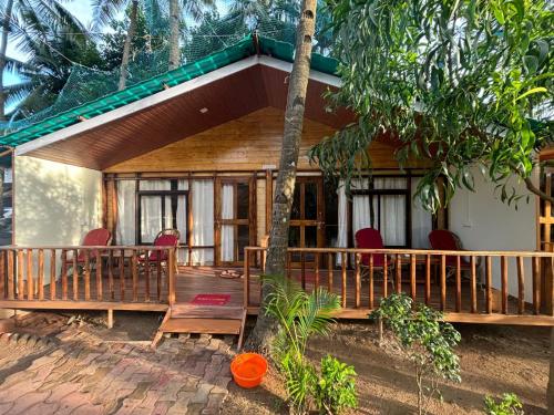 a wooden house with red chairs in front of it at Sonho do Mar in Agonda