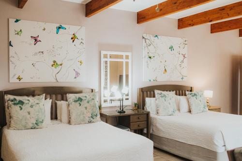 two beds in a bedroom with butterflies on the wall at Hadens Guesthouse in Nelspruit