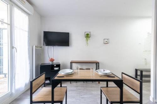 une salle à manger avec une table et des chaises et une télévision dans l'établissement Le Bougainvillier - charmant studio avec balcon, à Bussy-Saint-Georges