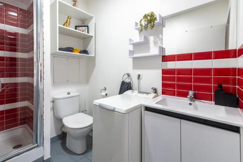 La salle de bains est pourvue d'un lavabo et de carreaux rouges. dans l'établissement Le Bougainvillier - charmant studio avec balcon, à Bussy-Saint-Georges