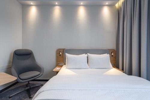 a hotel room with a bed and a chair at Holiday Inn Express Munich Airport - Erding by IHG in Erding