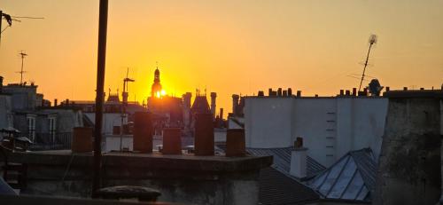 eine Skyline der Stadt mit Sonnenuntergang im Hintergrund in der Unterkunft Marais Rooftop Apartment in Paris