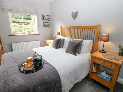 a bedroom with a bed with a tray of food on it at East Crossthwaite Cottage in Newbiggin