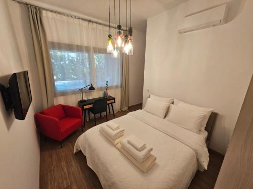 a bedroom with a white bed with a red chair and a window at TG NEW Luxury Private Resort & SPA Villas - Heated Salty Swimming Pool, Outdoor Jacuzzi, Sauna, Exotic Garden in Limassol
