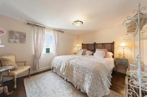 a bedroom with a bed and a chair and a window at Cottage On The Common in Great Malvern