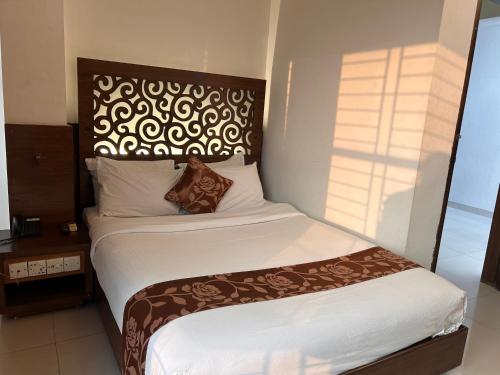 a hotel room with a bed with white sheets and a headboard at La Vista Hotel in Sylhet