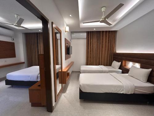 a hotel room with two beds and a television at La Vista Hotel in Sylhet