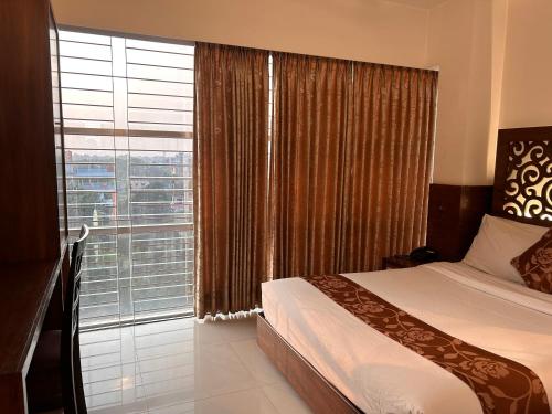 a bedroom with a bed and a large window at La Vista Hotel in Sylhet
