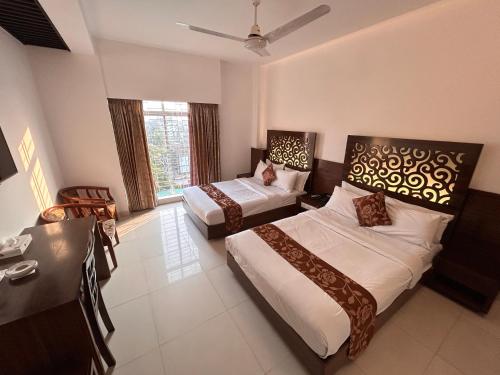 a hotel room with two beds and a desk at La Vista Hotel in Sylhet