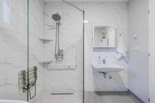 een witte badkamer met douche en wastafel bij Villa Great Escape in Šumet