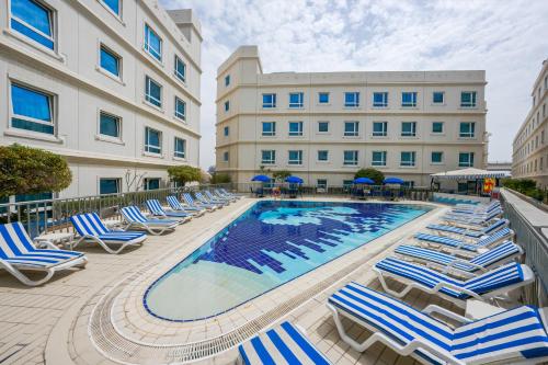 a swimming pool with lounge chairs and a hotel at Al Bustan Centre & Residence in Dubai