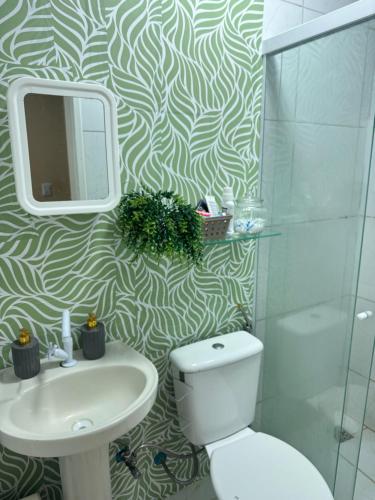 a bathroom with a toilet and a sink and a mirror at Suite climatizada em Ap compartilhado na ponta da areia in Vinhais