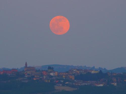 a red moon rising over a city in the sky at La Vigna del Parroco-2- in Serralunga d'Alba