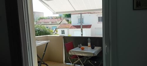 d'une table et d'une chaise sur un balcon avec une fenêtre. dans l'établissement Pti paradis, au Grau-dʼAgde