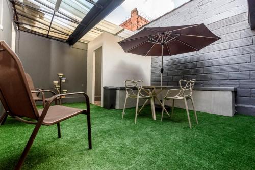 a table and chairs with an umbrella in a room at Hotel Hola Medellín in Medellín