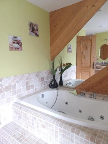 La salle de bains est pourvue d'une grande baignoire blanche et de murs verts. dans l'établissement Maison de village l autentic, à Aussois