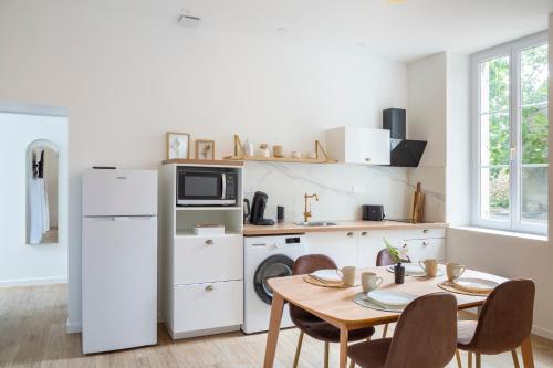 une cuisine avec une table et un réfrigérateur blanc dans l'établissement Le logis de Chambord, à Mont-près-Chambord