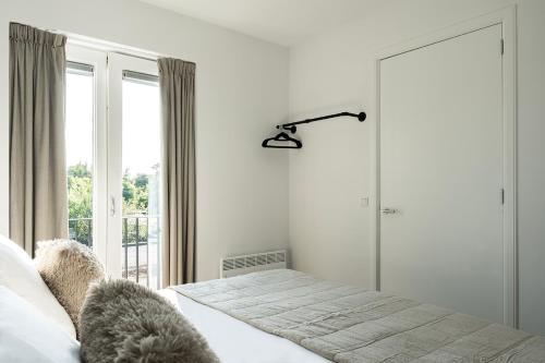 a white bedroom with a bed and a window at Newly Renovated XL home city center in Nijmegen