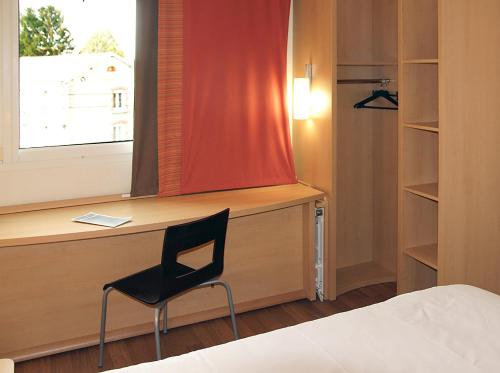 a bedroom with a desk and a chair next to a window at ibis Longwy Mexy in Mexy