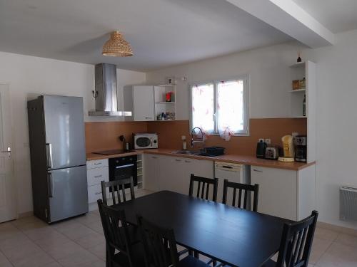 Il comprend une cuisine équipée d'une table noire et d'un réfrigérateur. dans l'établissement Villa BIENVENUE, à Andernos-les-Bains