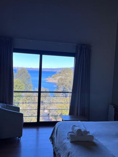 a bedroom with a large window with a view of the water at Costa de Lago - Cullelafquen in Villa Pehuenia