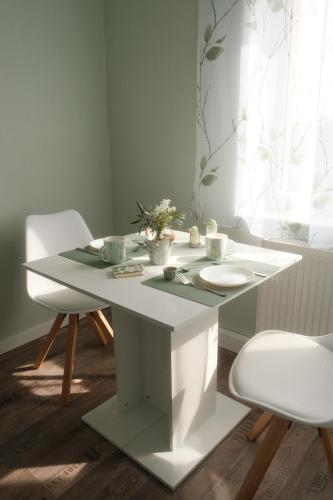 a white table with two chairs and a table with flowers on it at Zimmervermietung Hebenstreit in Bernburg