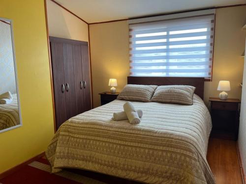 a bedroom with a bed with two pillows and a window at Hospedaje Brisas de Frutillar in Frutillar