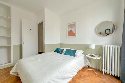 une chambre avec un lit blanc et un miroir dans l'établissement Flexliving - room - Septembre, à Paris