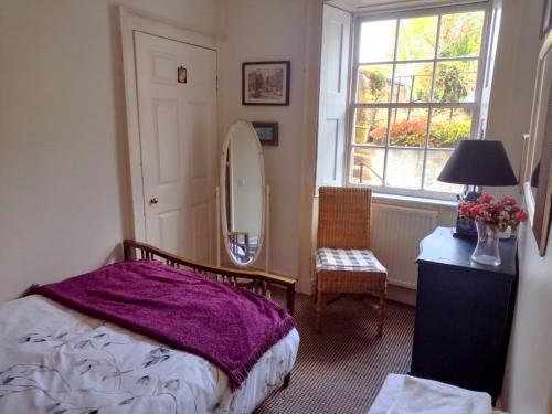 a bedroom with a bed and a mirror and a chair at Central Georgian Garden Flat with Free Parking in Bath