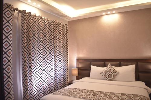 a bedroom with a bed and a wall with curtains at Shams Alweibdeh Hotel Apartments in Amman
