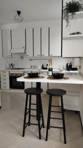 a kitchen with white cabinets and a counter with two stools at Braguti Apartments in Romano di Lombardia