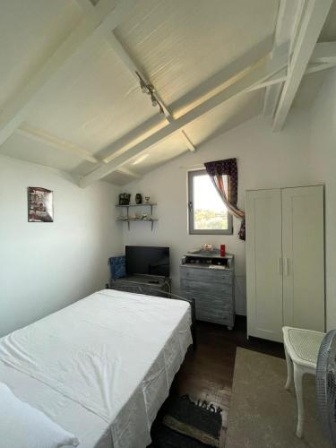a bedroom with a white bed and a desk at Simple Stay Vari's House in Vari