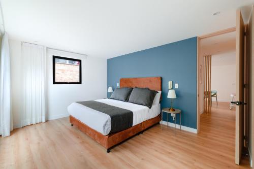 Un dormitorio con una cama y una pared azul. en Cora 96 Street Apartments, en Bogotá