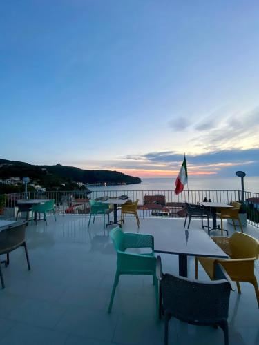 a group of tables and chairs on a patio with the ocean at B&B degli Aranci in Palinuro