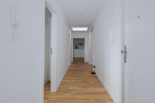 an empty hallway with white walls and wooden floors at Stylish & Bright Apartment in Top Location in Baunatal