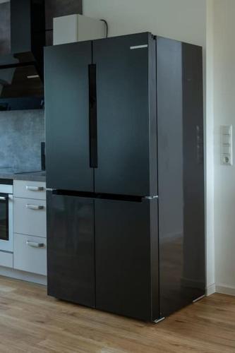 a large black refrigerator in a kitchen at Stylish & Bright Apartment in Top Location in Baunatal