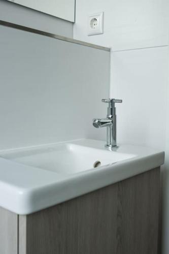 a white sink in a bathroom with a wooden cabinet at Stylish & Bright Apartment in Top Location in Baunatal