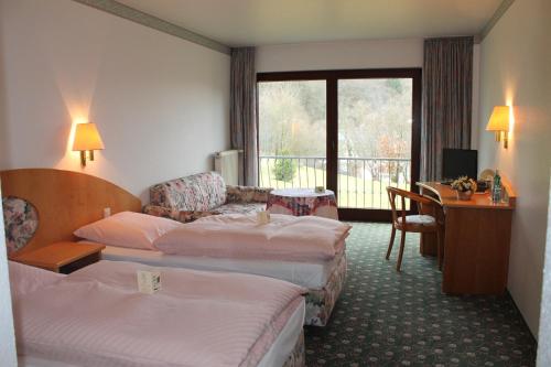 a hotel room with two beds and a desk at Landgasthof Hotel Zur Linde im Taunus in Gemünden